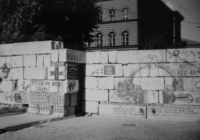 Mauer mit Aufschriften, dahinter Geb&auml;ude im Rundbogenstil