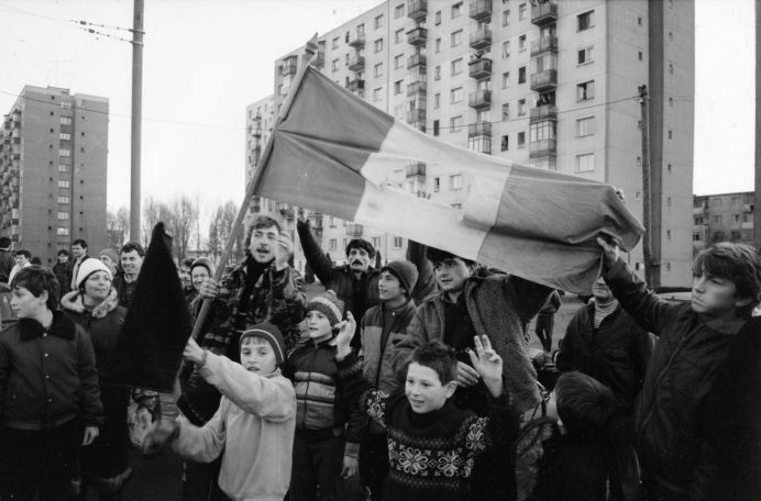 Foto: Menschenmenge mit rumänischer Fahne vor einem Wohnblock.
